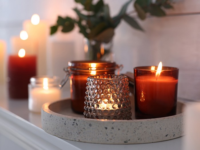 dark brown glass votive candles on a granite white plate on a fireplace mantel